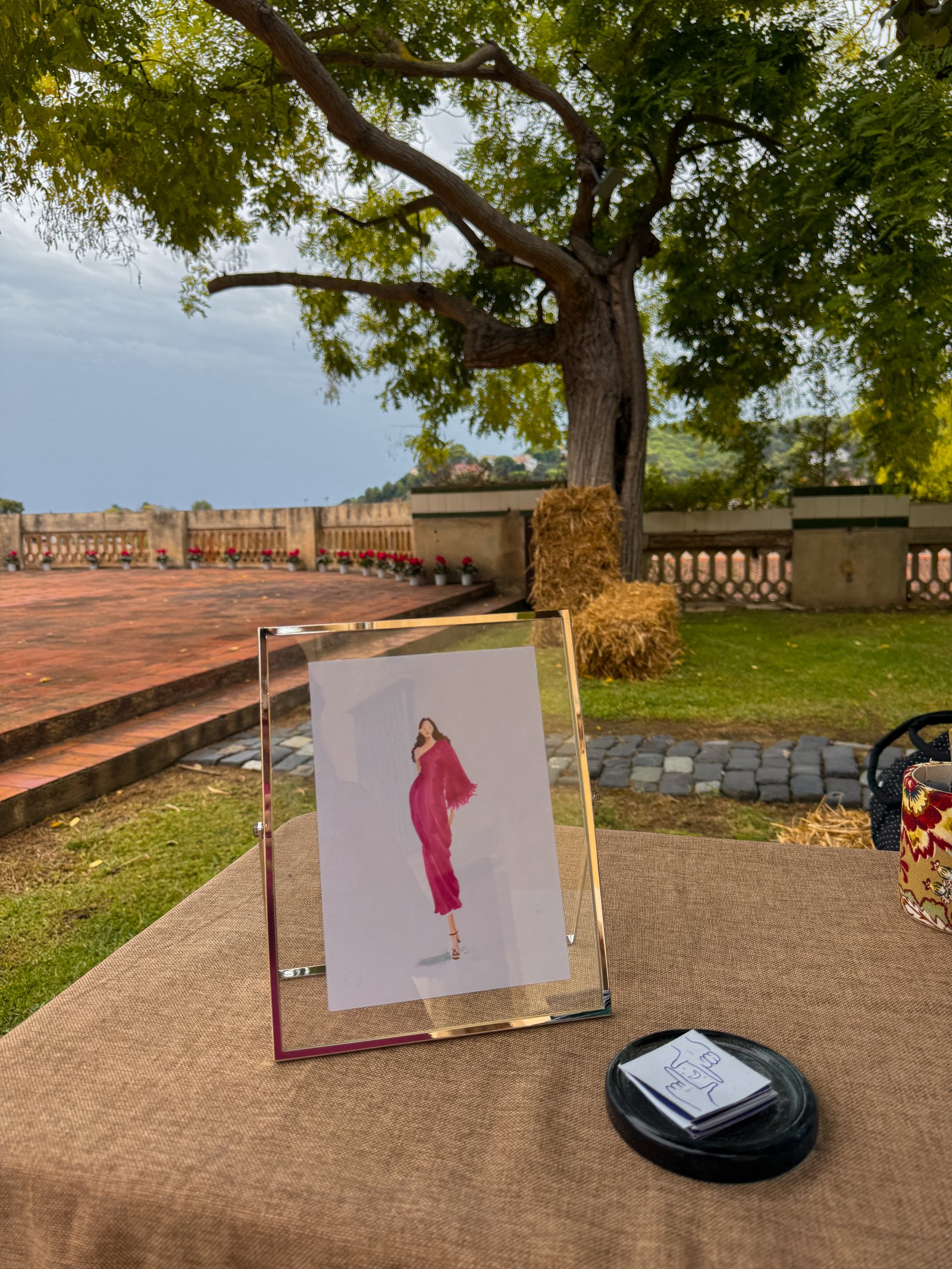 Retrato de una invitada enmarcado sobre una mesa del jardín de Can Ratés